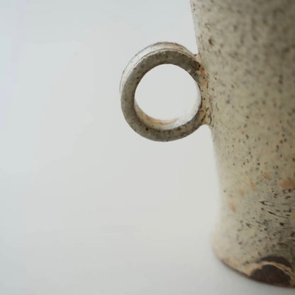 Close-up of a ceramic mug with a speckled texture on a light gray background