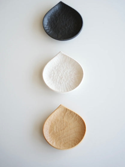 Three ceramic dishes in black, white, and beige on a light gray background