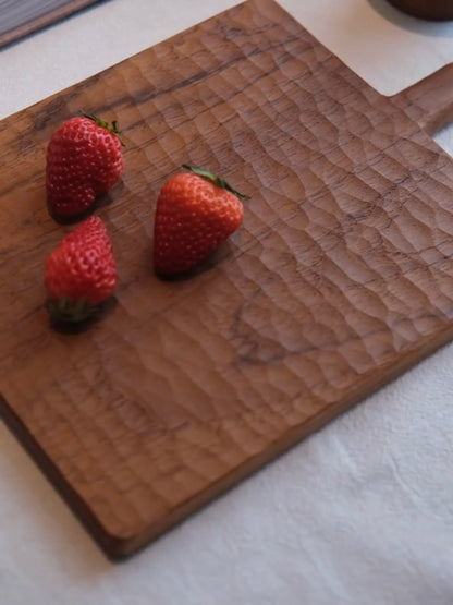 Three strawberries on a wooden cutting board