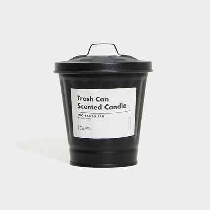 Black trash can-shaped candle with a label on a white background