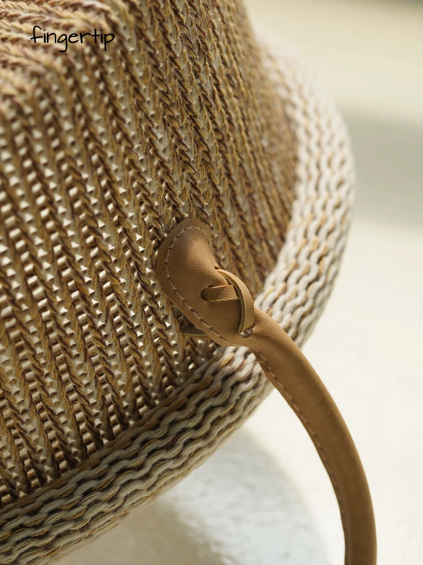 Close-up of a woven straw bag with a leather strap on a blurred background